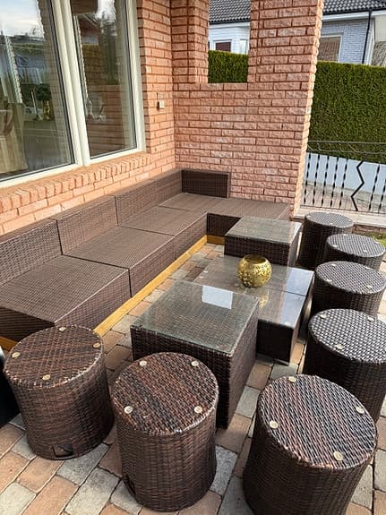 Brun konstrotting loungesoffa med bord och pallar för uteplats