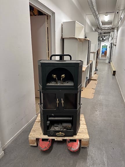 Svart vedkamin med glasluckor och mässingsdetaljer