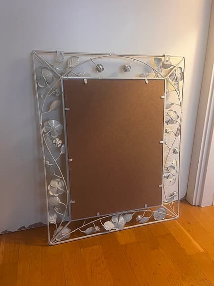 spegel med vit metallram och blommor