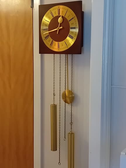 Väggklocka med pendel i guld och trä
