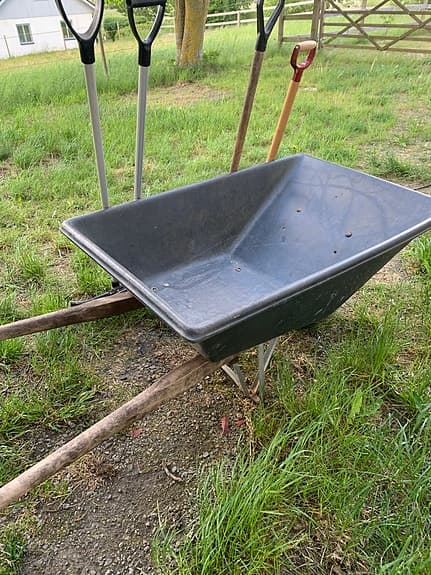 Stor skottkärra och redskap för att mocka ut häst box.
