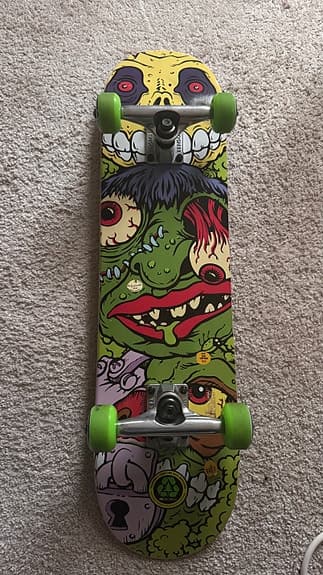 Skateboard med färggrafik och gröna hjul