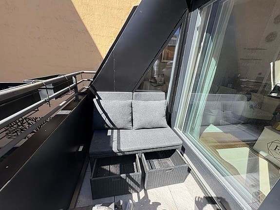 Mörkgrå balkongsoffa med förvaring och dynor