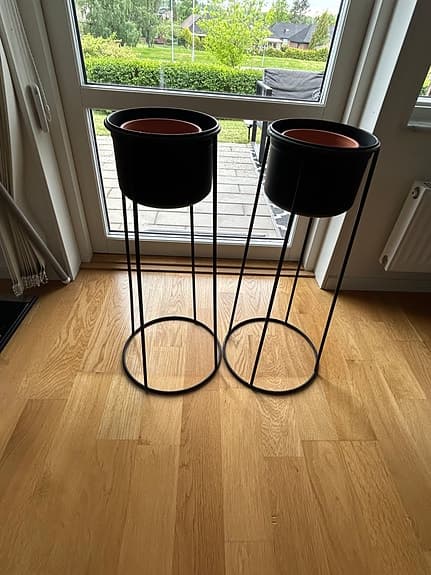 Svarta blomkrukor på ställning i metall