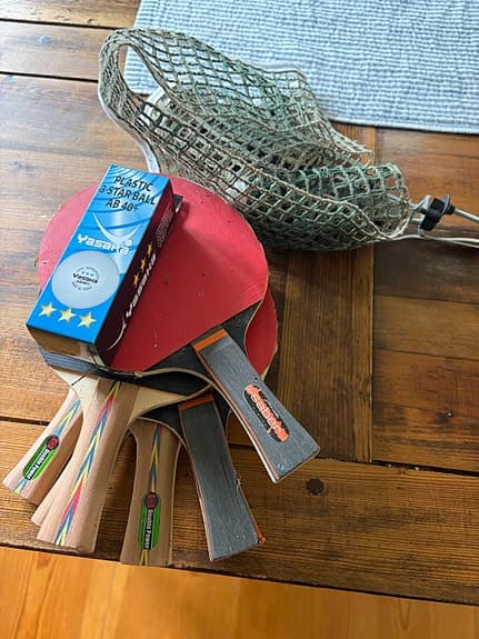 Bordtennisbord med nät och flera racketar