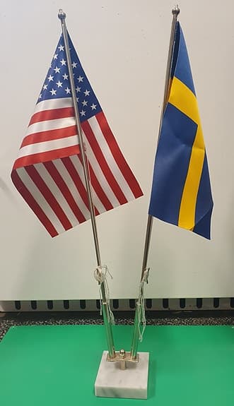 Flaggstång med två flaggor för bord/hylla inne.