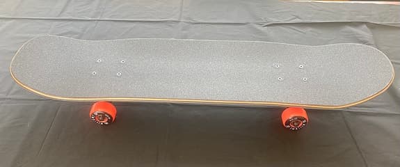 Skateboard med färggrafik och orange hjul