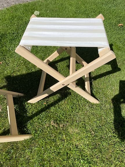 Hopfällbara, stabila pallar i trä klädda med randigt tyg.