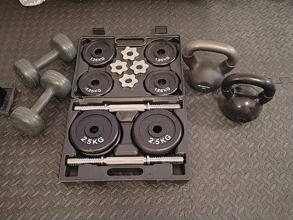 Träningsbänk med matta, hantelset och kettlebells