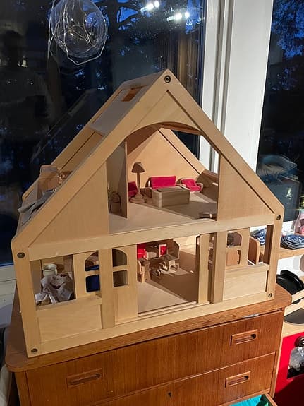 Trähus dockskåp med  skjutdörrar och möbler och dockor. Plan Toys