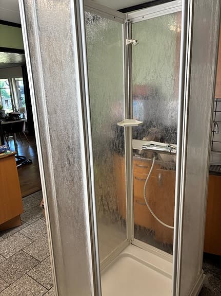 Duschkabin med duschblandare och hylla