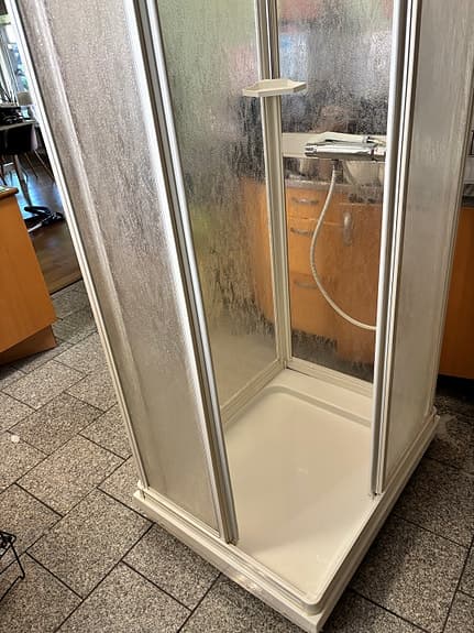 Duschkabin med duschblandare och hylla