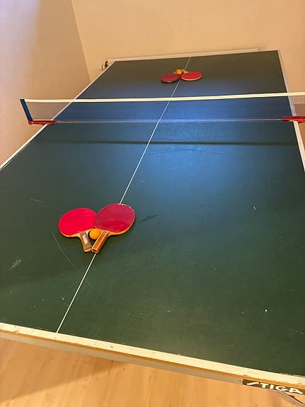 Bordtennisbord med nät, racketar och bollar