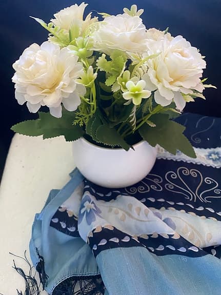 en konstgjord blomsterarrangemang med vita blommor i en vit kruka.