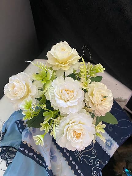 en konstgjord blomsterarrangemang med vita blommor i en vit kruka.