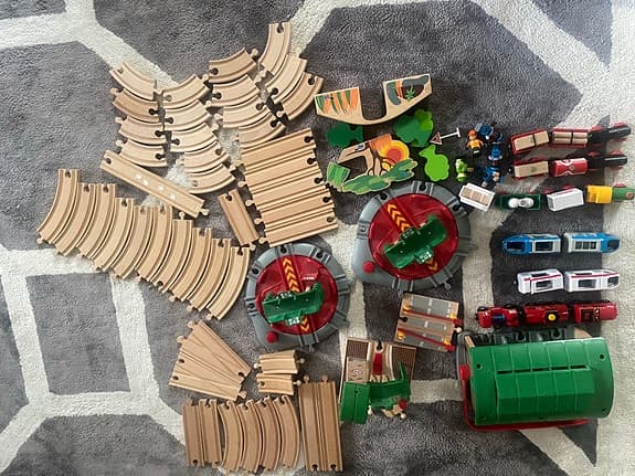 BRIO tågbana med flera lok, vagnar och stationsbyggnader.