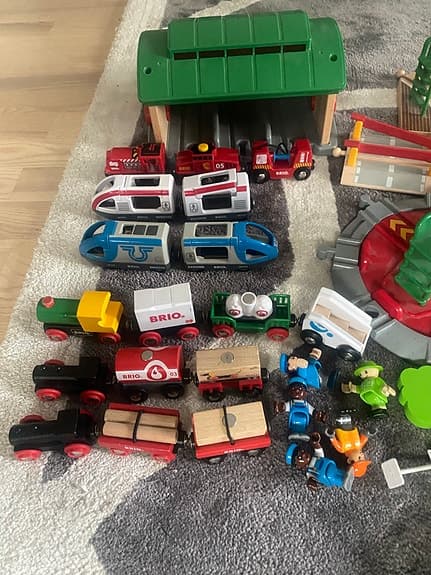 BRIO tågbana med flera lok, vagnar och stationsbyggnader.