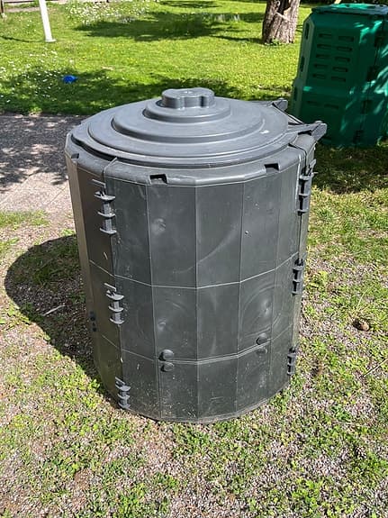 Svart kompostbehållare trädgård