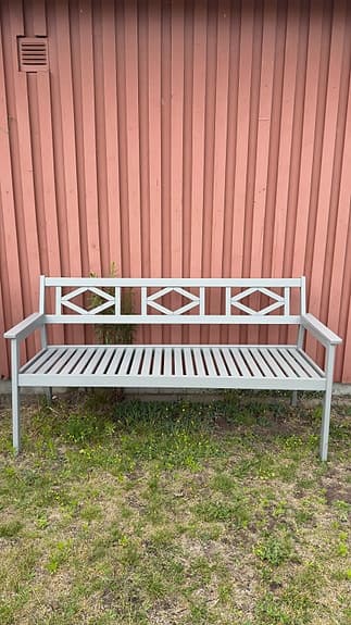 Grå trädgårdsbänk i trä med armstöd