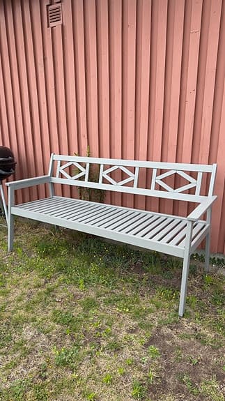 Grå trädgårdsbänk i trä med armstöd