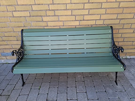 Grön trädgårdsbänk med gjutjärnssidor
