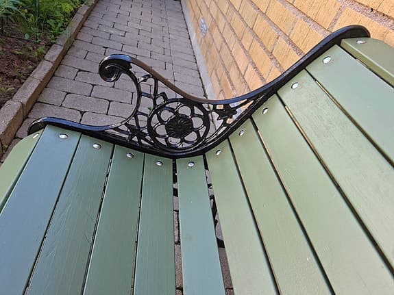 Grön trädgårdsbänk med gjutjärnssidor