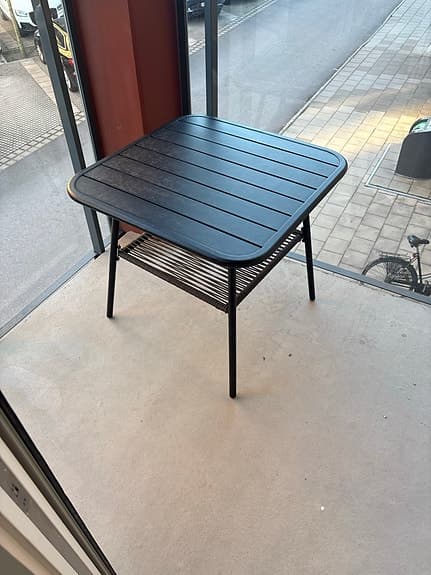 Svart metallutebord med hylla