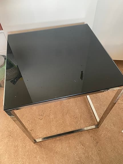 ett modernt satsbord med en svart glasskiva och en kromad metallram