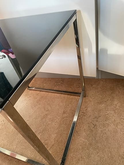 ett modernt satsbord med en svart glasskiva och en kromad metallram