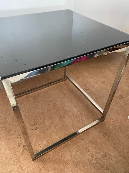 ett modernt satsbord med en svart glasskiva och en kromad metallram