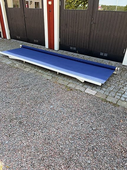 Blå terrassmarkis med vev och väggfästen