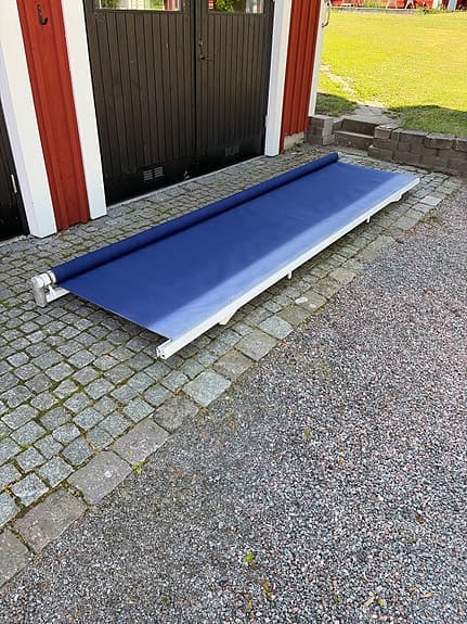 Blå terrassmarkis med vev och väggfästen