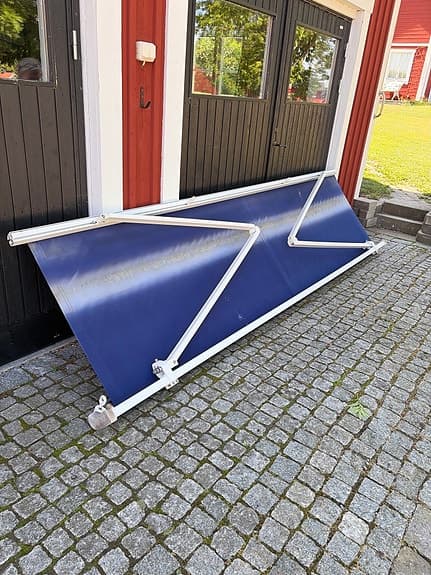 Blå terrassmarkis med vev och väggfästen