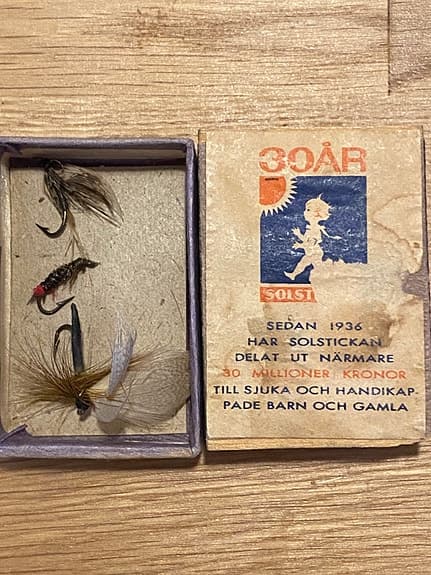 Solstickan ask med äldre flugor för flugfiske.