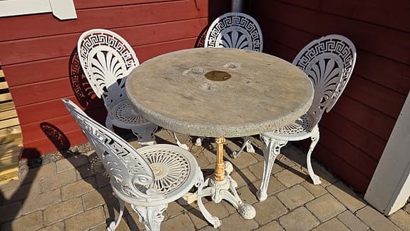 Runt trädgårdsbord med fyra vita stolar i gjutjärn