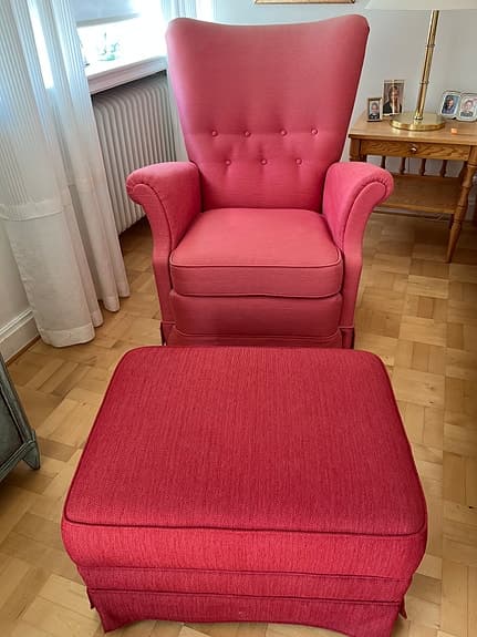 Fåtölj klädd i tyg från Svenskt tenn. Fotpall i rödare nyans.