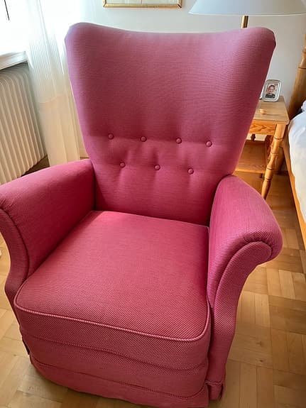 Fåtölj klädd i tyg från Svenskt tenn. Fotpall i rödare nyans.