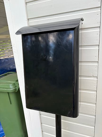 Svart postlåda/brevlåda på stolpe
