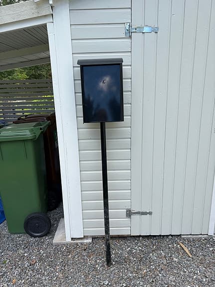 Svart postlåda/brevlåda på stolpe