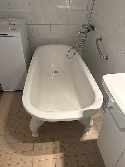Vitt fristående badkar på fötter
