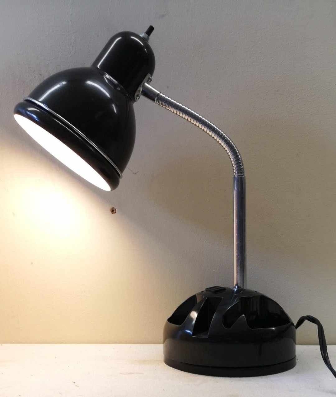Svart skrivbordslampa med böjbar hals och förvaringsutrymme på foten