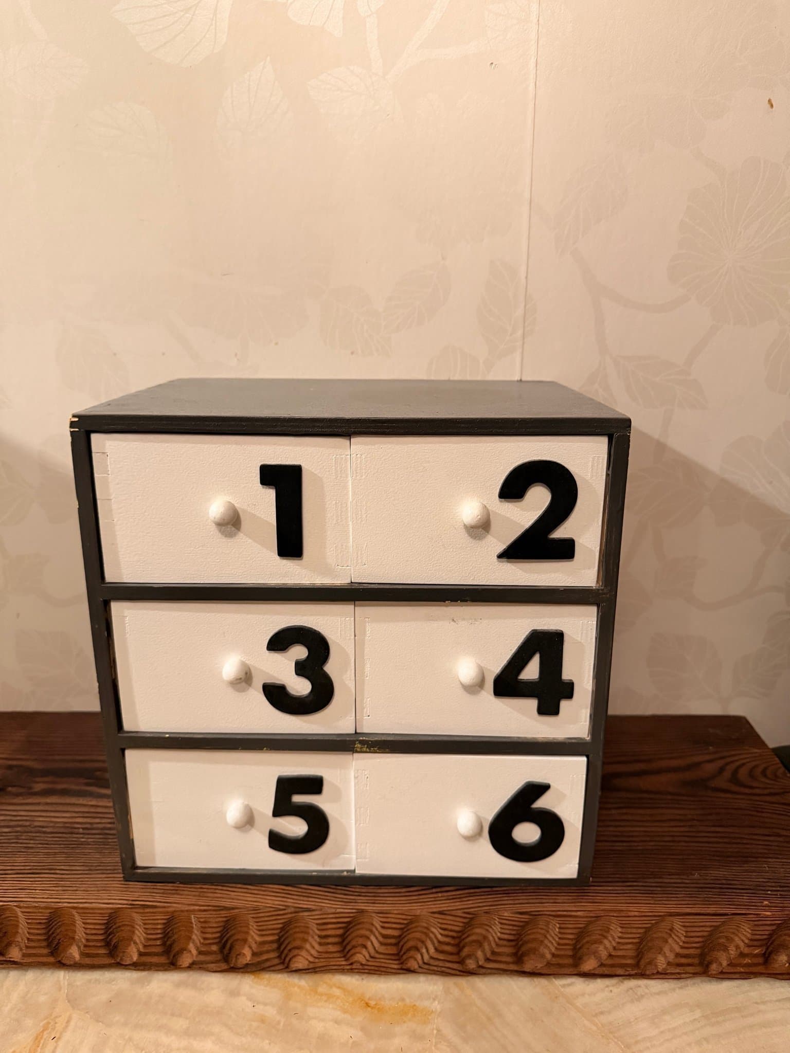 Liten byrå med numrerade lådor i trä