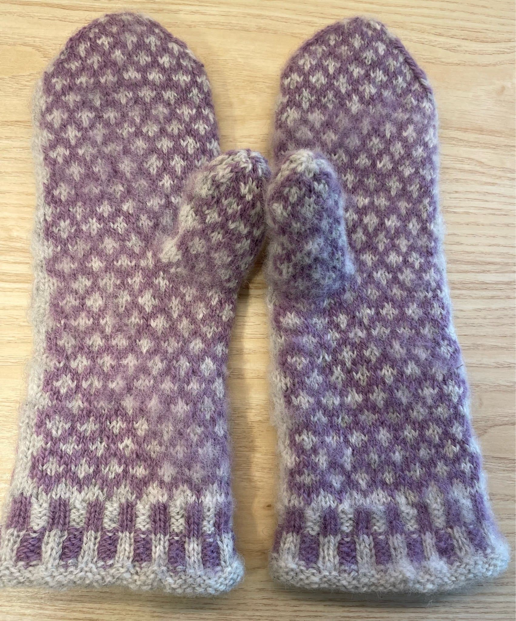 Handstickade ullvantar, ljusgrå och lila.