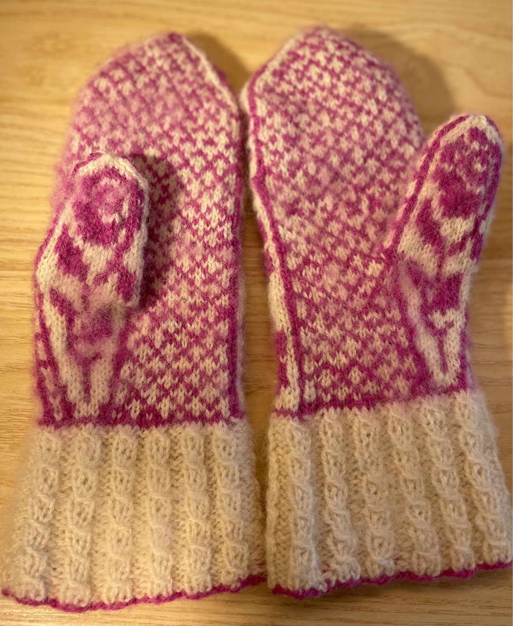 Handstickade ullvantar, rosalila rosor på vit botten.