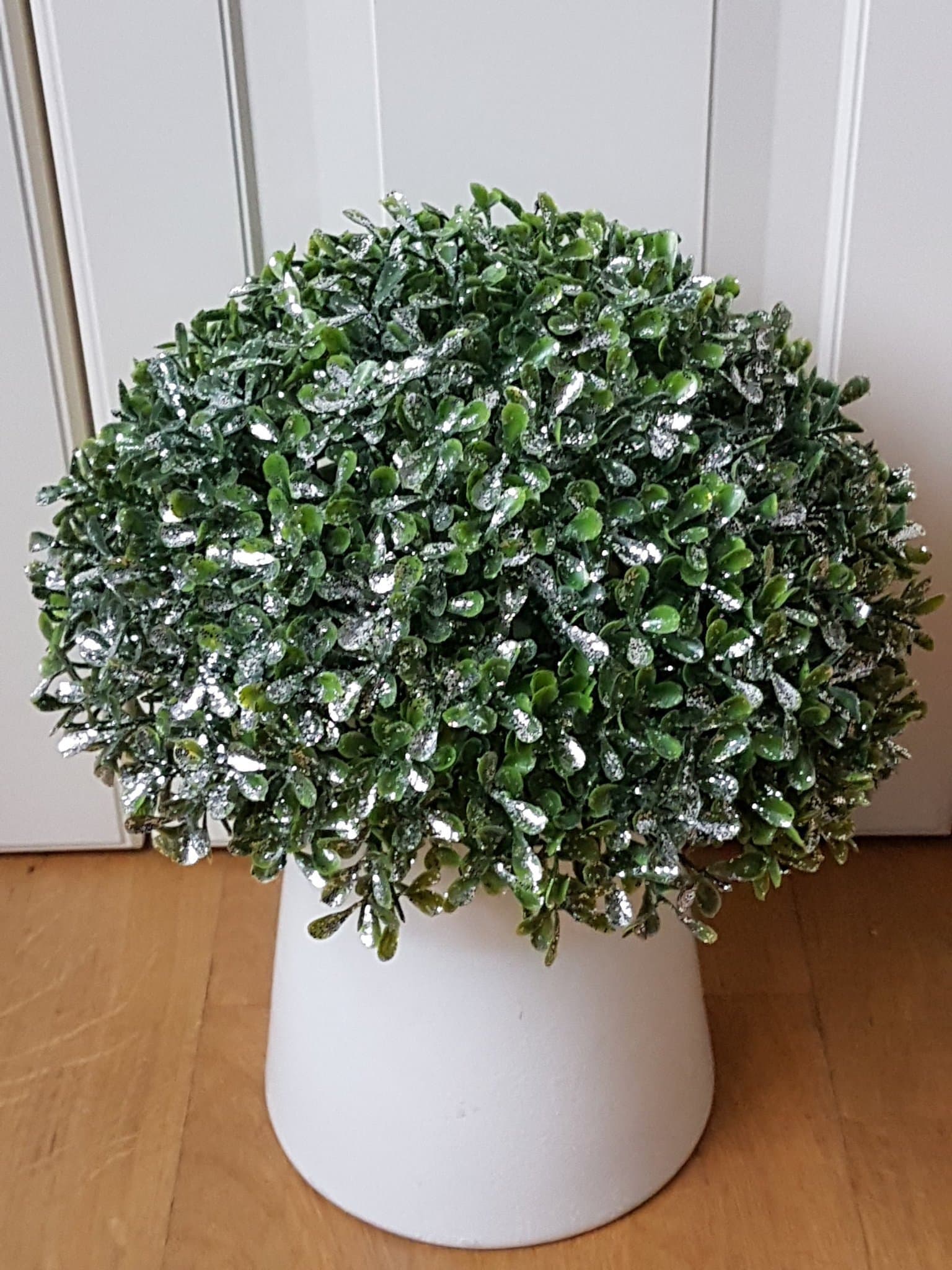 Vacker glittrande buxbom i kruka. En konstväxt med täta blad.