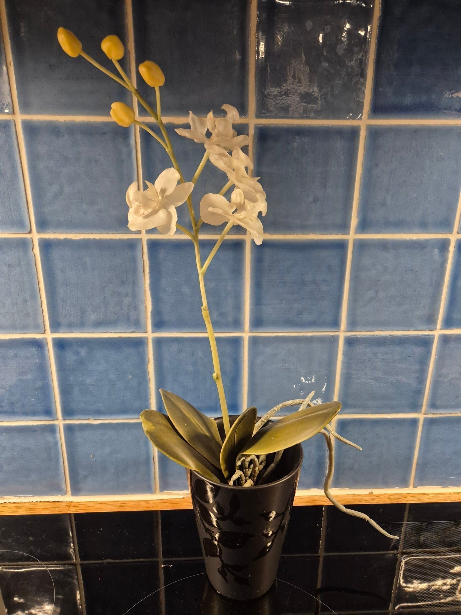 Konstgjord naturtrogen vit orkidé i svart elegant kruka