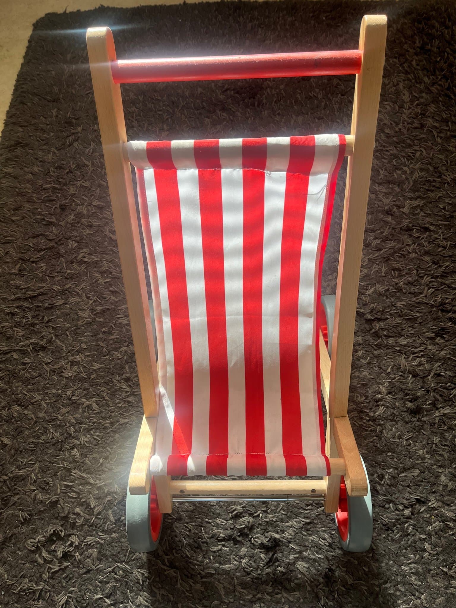 Dockvagn i trä med röd- och vitrandigt tyg från Egmont Toys