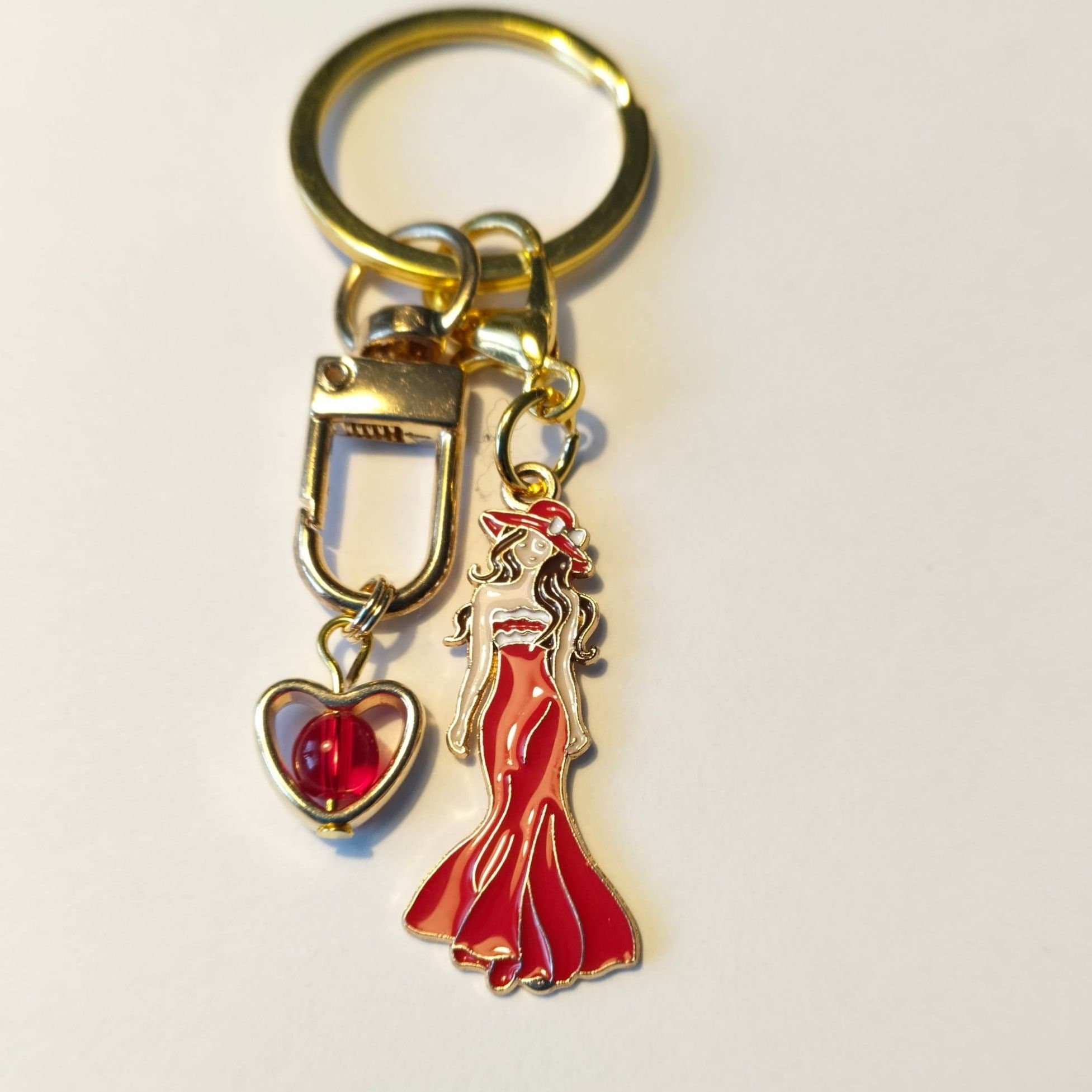 Fin Nyckelring med kvinna i Röd klänning och guld hjärta med röd pärla inuti