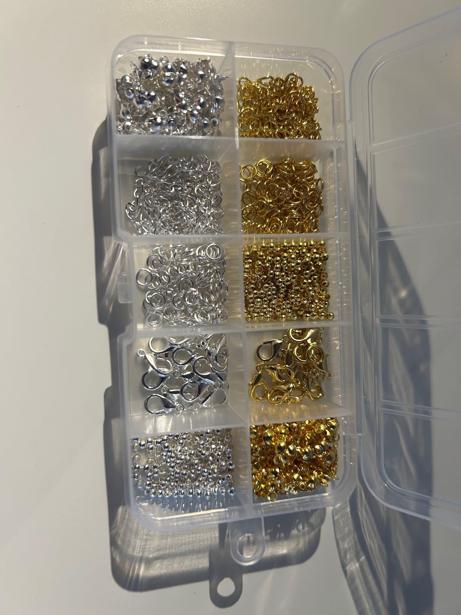 Låda med blandade smyckestillbehör se bild 2 i guld och silverfärg