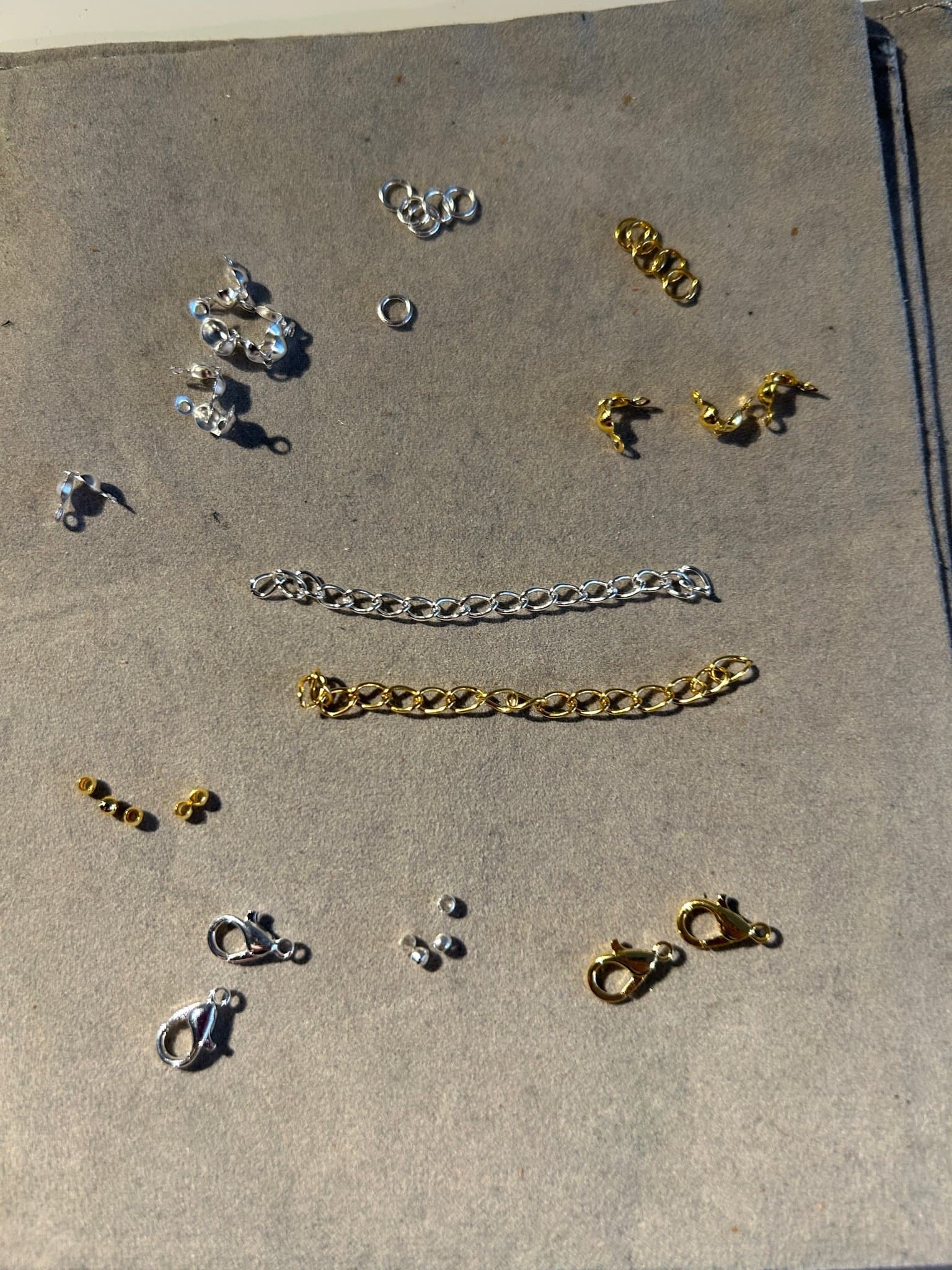 Låda med blandade smyckestillbehör se bild 2 i guld och silverfärg